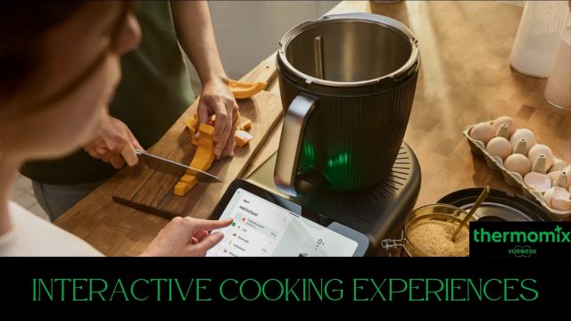 A-Thermomix-consultant-in-a-green-apron-offers-product-guidance-to-attendees-at-a-kitchen-demo-with-food-and-sunflowers-on-the-counter.