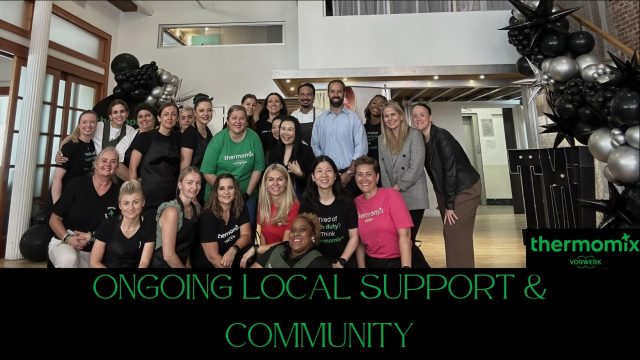 Large-group-of-Thermomix-users-and-consultants-smiling-together-at-a-local-community-support-event,-with-festive-black-and-silver-balloons-in-the-background.